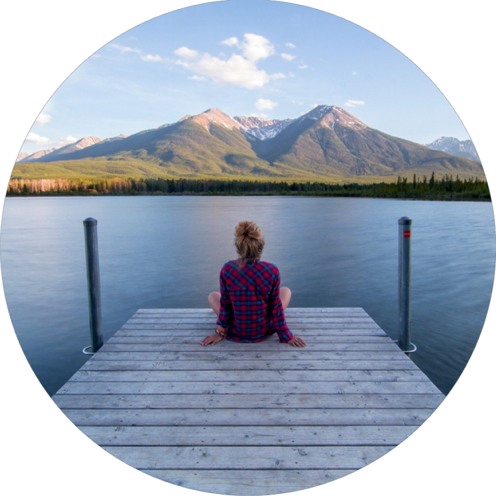  Bild Frau sitzt am Ufersteg und schaut auf die Berge im Hintergrund